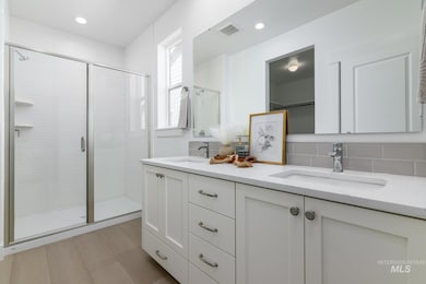 Bathroom with double vanity, a stall shower, recessed lighting, and backsplash
