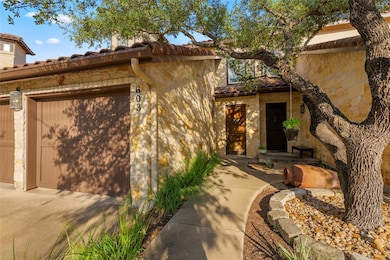 View of exterior entry with a tiled roof, stone siding, and a garage