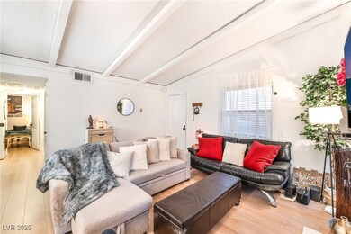 Living room with light wood finished floors and beamed ceiling