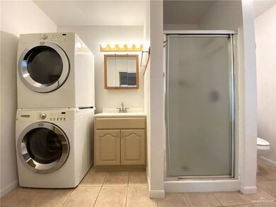 Clothes washing area featuring stacked washer / drying machine, sink, and light tile patterned floors