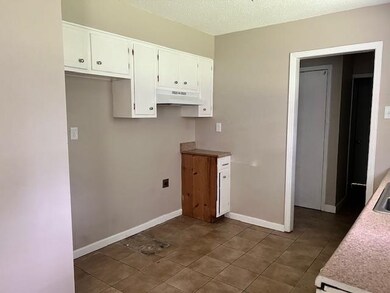 Kitchen with a textured ceiling, white cabinets, a