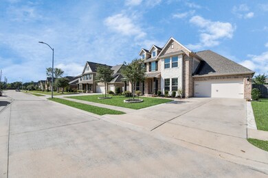 This is a spacious two-story home with a brick facade, featuring an attached two-car garage and a neatly manicured lawn. The house is located on a well-kept gated street with similar properties.