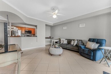 Living room featuring ceiling fan, ornamental molding, and light tile patterned floors