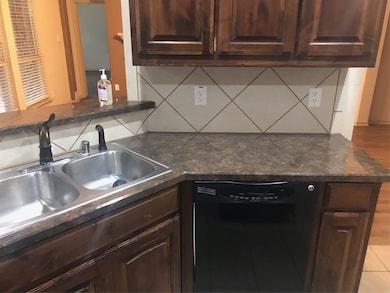 Kitchen with dishwashing machine, a sink, decorative backsplash, and dark brown cabinets