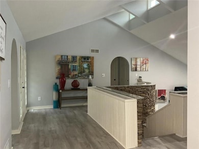 Front entryway featuring arched walkways, light wood-style flooring, and an open layout leading into the main living area.