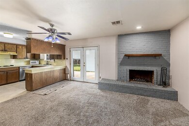 Kitchen featuring a brick fireplace, light carpet,
