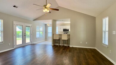 Unfurnished living room with dark wood-type flooring, french doors, vaulted ceiling, and a ceiling fan
