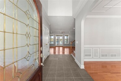 Foyer with ornamental molding, stairs, dark tile patterned flooring, arched walkways, and baseboards