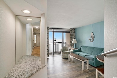 Living area featuring a textured wall, wood finished floors, and expansive windows