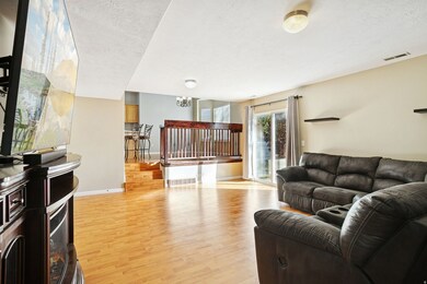 Living area featuring light wood-style floors, a textured ceiling, and a chandelier