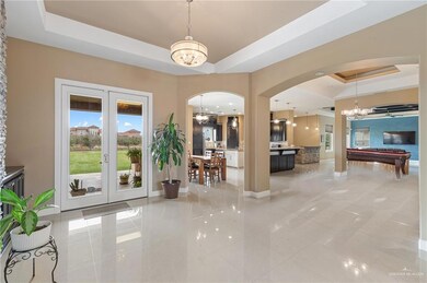 Tiled entrance foyer featuring a notable chandelier, french doors, and a raised ceiling
