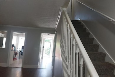 Stairway featuring ornamental molding, plenty of natural light, a textured ceiling, and wood finished floors