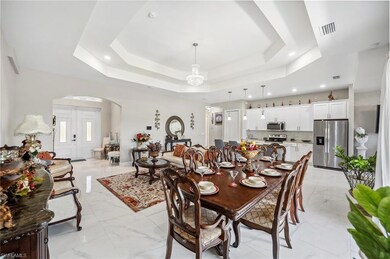 Dining area featuring light marble finish flooring, arched walkways, and a tray ceiling