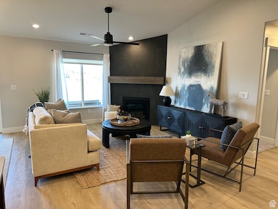 Living room featuring a large fireplace, light wood-style floors, recessed lighting, ceiling fan, and lofted ceiling