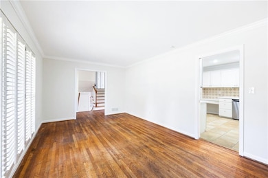 Spare room with light wood-type flooring, crown molding, and stairs