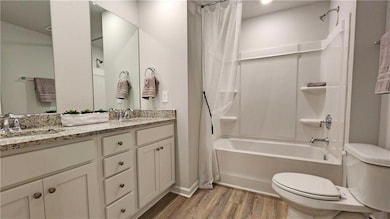 Full bath featuring shower / bath combo with shower curtain and light wood-style flooring