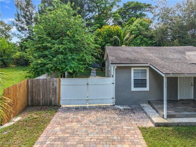 View of home's exterior with a gate, a patio, stucco siding, and a shingled roof