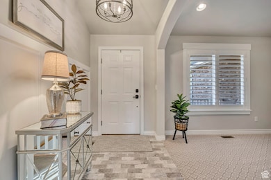 Entrance foyer with a chandelier, recessed lighting, and light carpet
