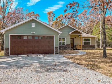 Ranch-style home with concrete driveway, stone siding, covered porch, and an attached garage