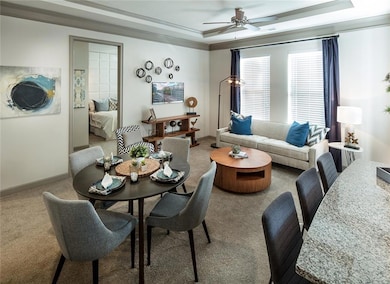 Carpeted living room featuring ceiling fan, a rais