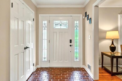 Entrance foyer with healthy amount of natural light, baseboards, brick floors, and ornamental molding
