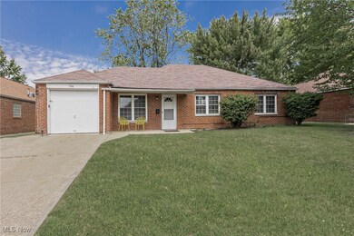 Ranch-style house featuring concrete driveway, a front yard, a shingled roof, an attached garage, and brick siding