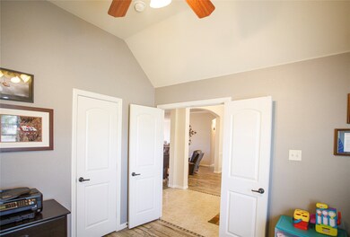 Bedroom with arched walkways, light wood-style flooring, vaulted ceiling, and ceiling fan