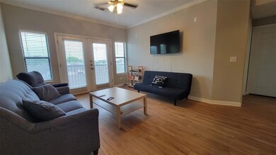 Living area with crown molding, wood finished floors, ceiling fan, and french doors