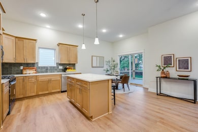 Kitchen featuring backsplash, a breakfast bar, black gas range oven, a center island, and healthy amount of natural light