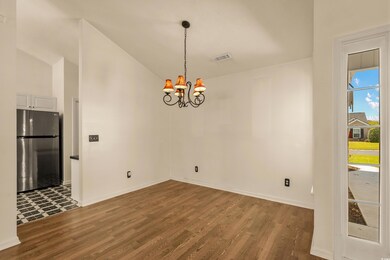 Unfurnished dining area featuring visible vents, baseboards, a notable chandelier, and wood finished floors