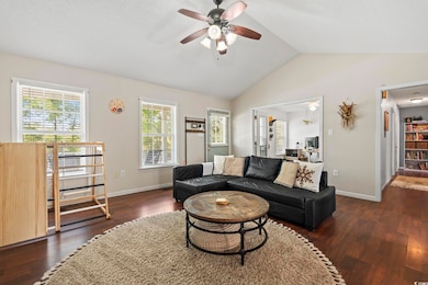 Living room featuring baseboards, a ceiling fan, wood finished floors, and vaulted ceiling