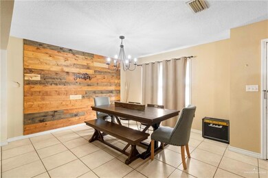 Dining area featuring light tile patterned floors, a textured ceiling, an inviting chandelier, and wood walls