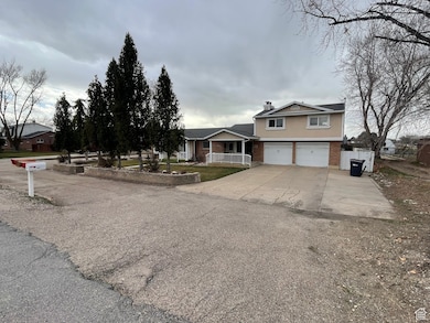 View of front of property with a garage, concrete driveway, brick siding, and a chimney