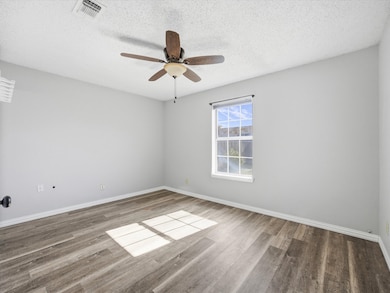 Empty room with a textured ceiling, wood finished floors, and ceiling fan