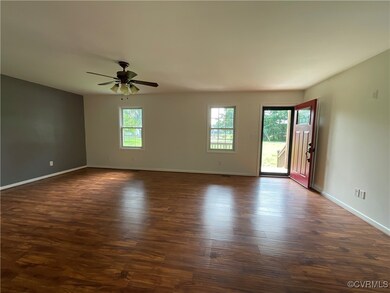 Living room with ceiling fan and dark wood-type flooring