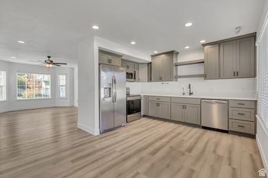Kitchen with open shelves, stainless steel appliances, gray cabinets, recessed lighting, and light countertops