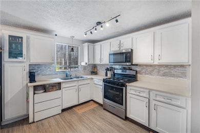 Kitchen with light countertops, a sink, white cabi