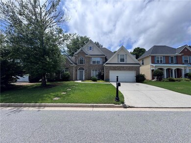 Traditional home featuring concrete driveway, brick siding, a front yard, and a garage