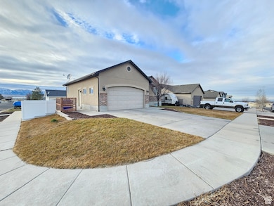 Exterior space featuring stucco siding, concrete driveway, an attached garage, a front yard, and fence