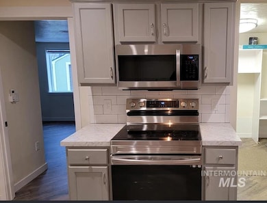 Kitchen featuring appliances with stainless steel finishes, decorative backsplash, gray cabinets, and light countertops