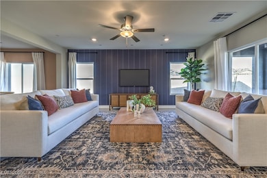 Living area featuring ceiling fan and wood walls