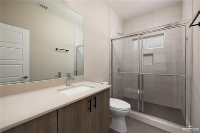 Bathroom with tile patterned floors, vanity, toilet, and a shower with door