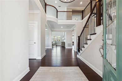 Foyer with crown molding, a towering ceiling, wood finished floors, stairway, and a chandelier