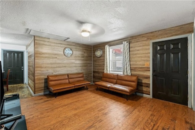 Sitting room with attic access, a textured ceiling, and wood finished floors