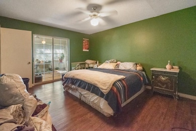 Bedroom with access to outside, a textured ceiling, dark wood-type flooring, and a ceiling fan