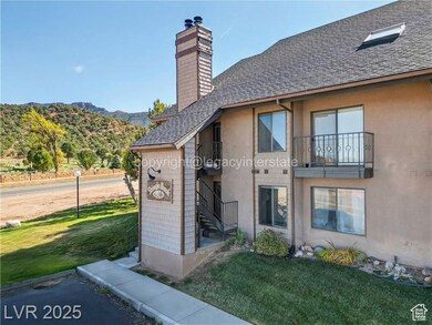 Rear view of house featuring a lawn, stucco siding, a chimney, and a shingled roof