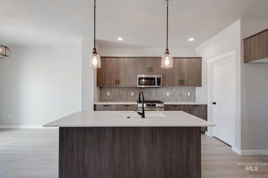 Kitchen with pendant lighting, modern cabinets, stainless steel appliances, backsplash, and light stone countertops