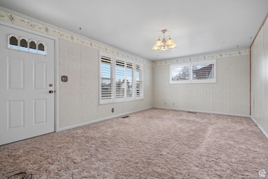 Interior space featuring visible vents, baseboards, an inviting chandelier, and wallpapered walls
