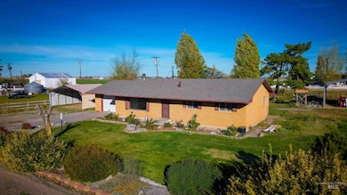 View of front facade featuring brick siding, a front yard, and driveway