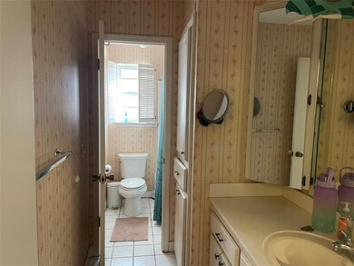 Bathroom with a shower with shower curtain, light tile patterned floors, wallpapered walls, and vanity